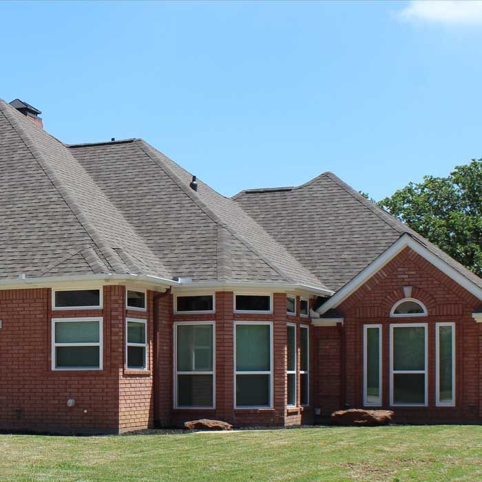 A brick house with a gray roof and white windows