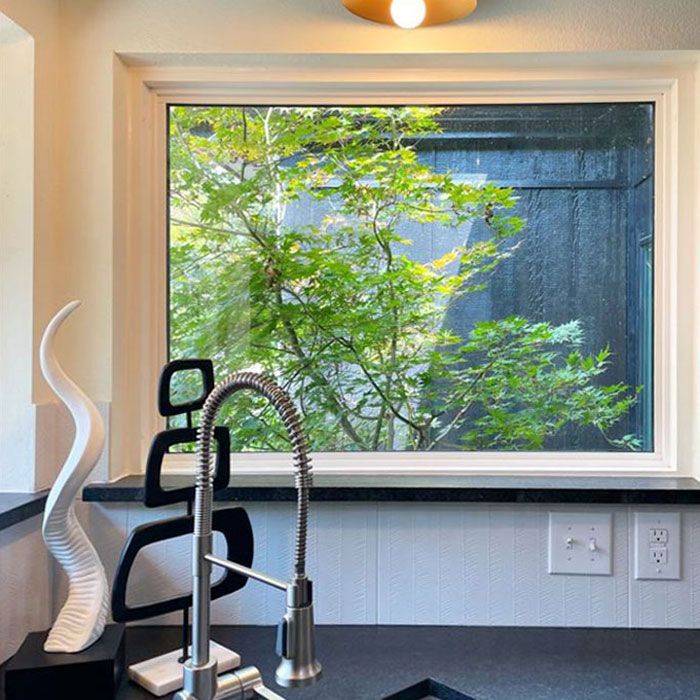 A kitchen with a sink and a window with a view of trees