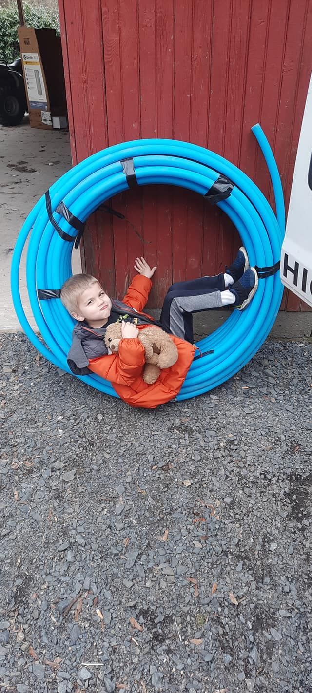 one of the owners sons laying in a blue pipe