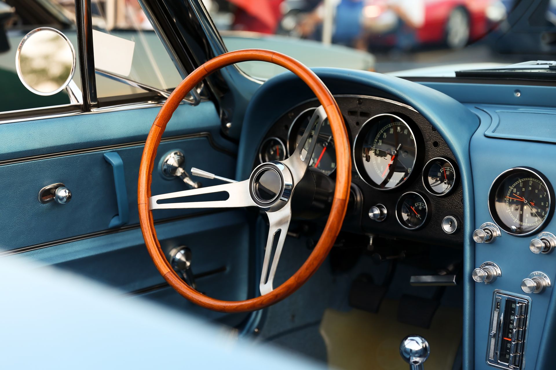 Classic car interior with wood steering wheel and blue dashboard.