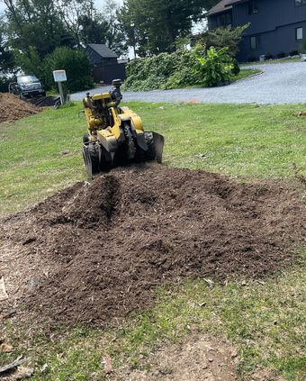 A stump grinder is cutting a tree stump in a yard.