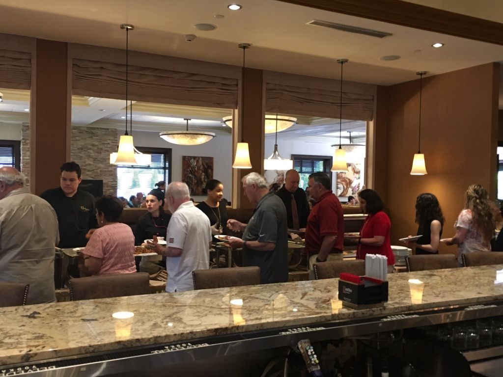 People chatting in a hotel lobby bar under hanging lights, with a granite countertop in the foreground.