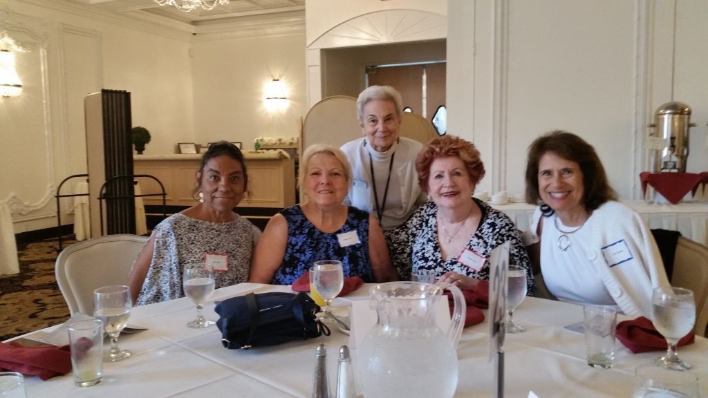 Four people smiling at a banquet table in a bright dining room