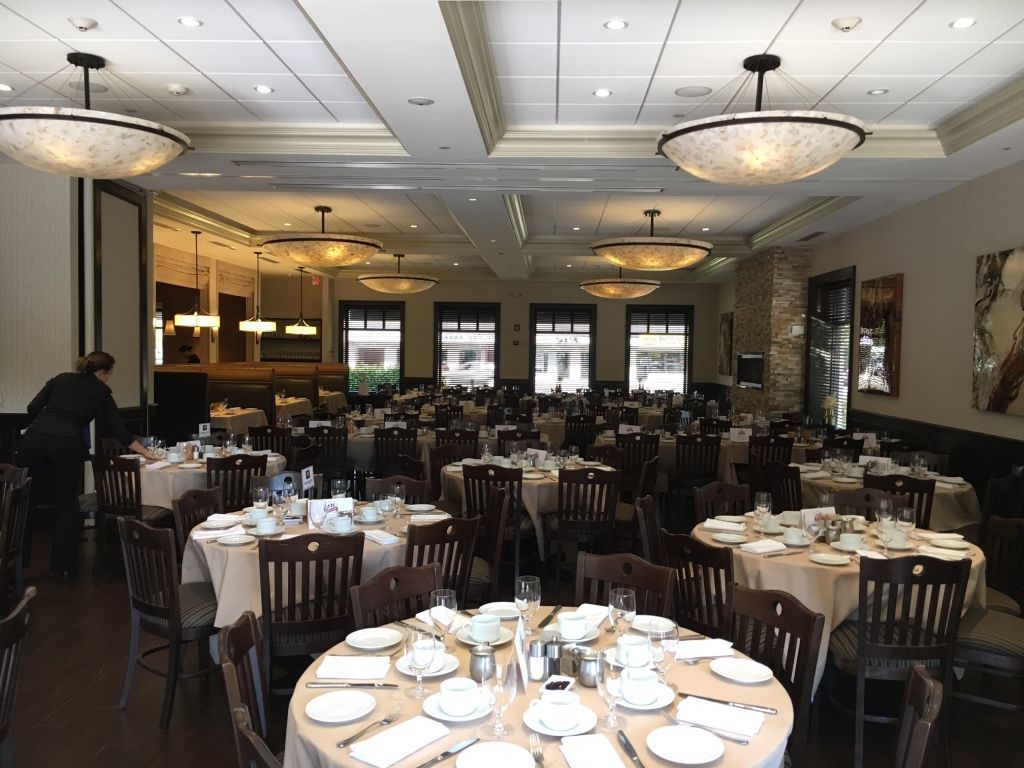 Elegant banquet hall with round tables set for dining and chandeliers overhead