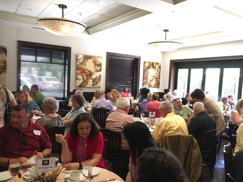 Crowded restaurant dining room with many people seated at tables under bright hanging lights