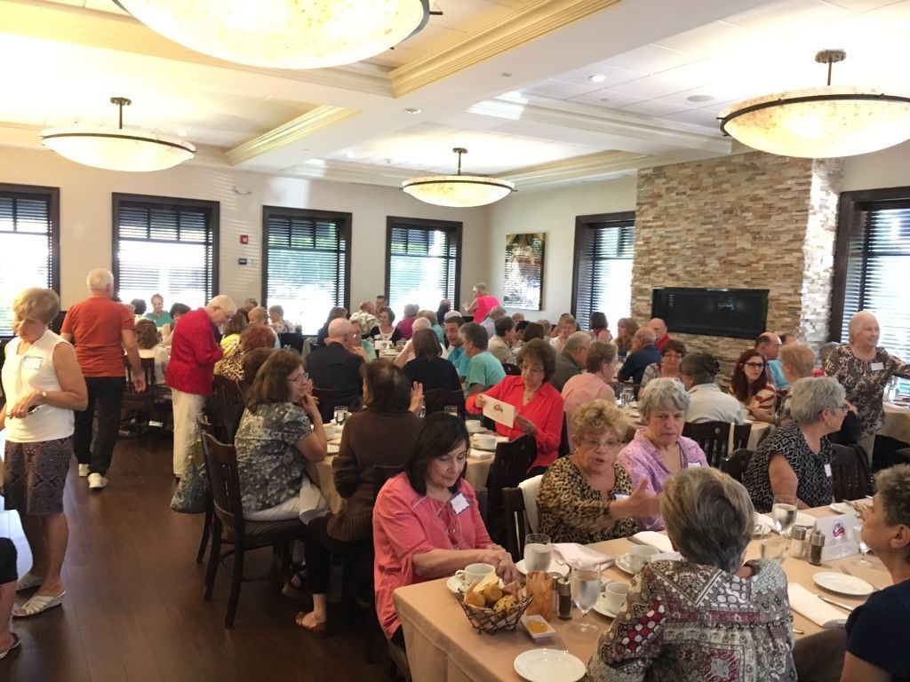 Crowded banquet hall with people seated at round tables during a social gathering