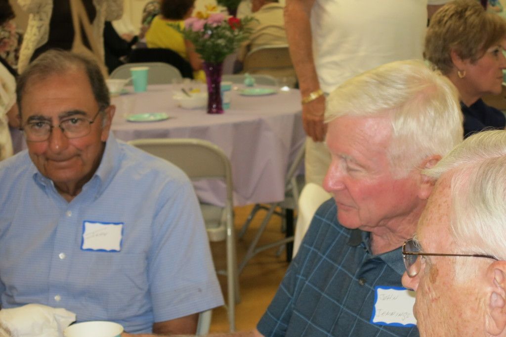 Three people seated at a table in a banquet hall, chatting during a gathering
