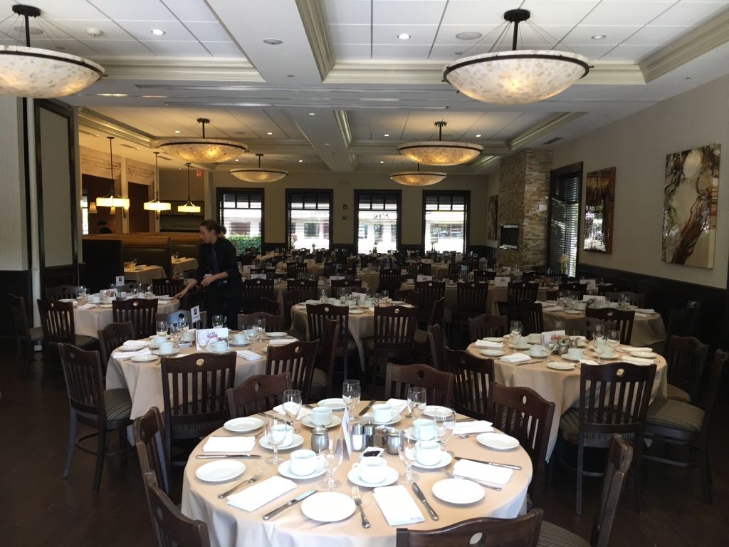 Elegant banquet hall with round tables set for dining under warm chandeliers