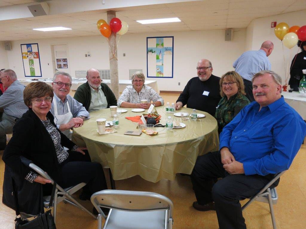 People seated around a decorated table at a small indoor celebration.