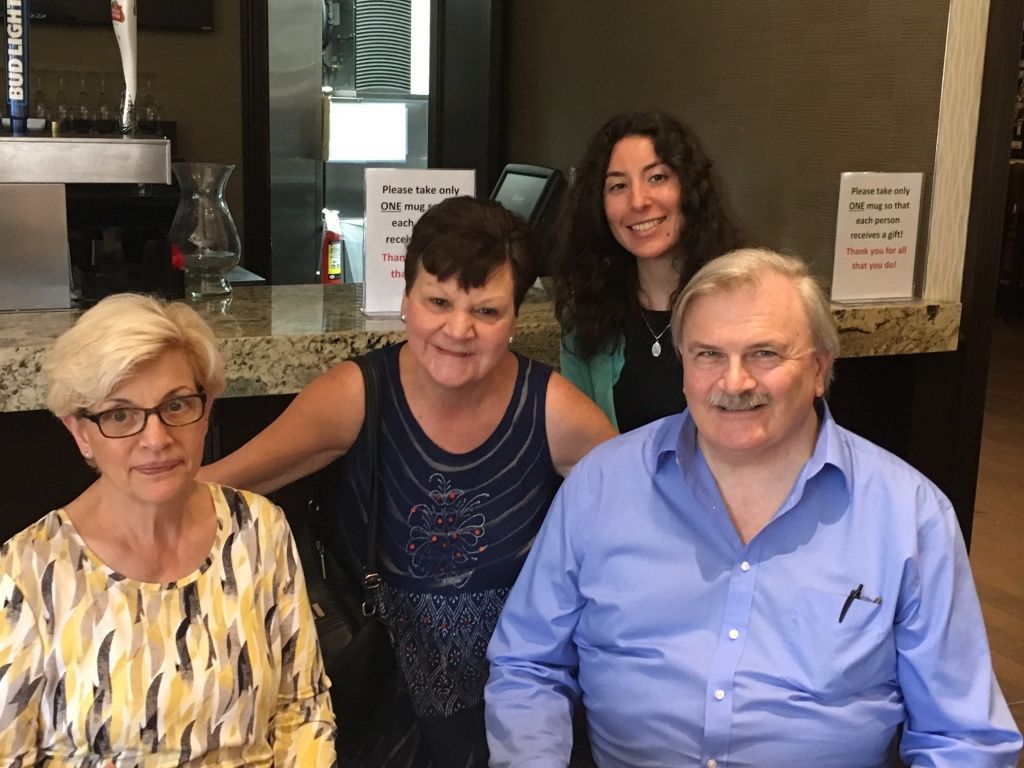 Four people posing together indoors, smiling in front of a lobby counter.