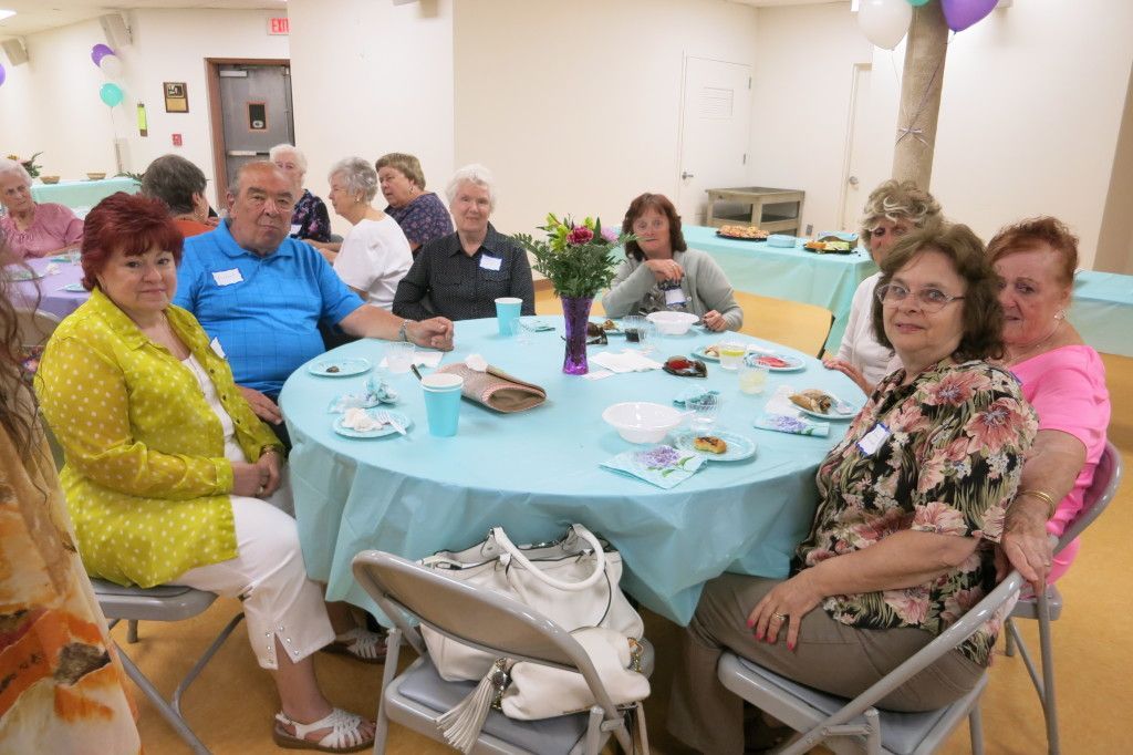 People seated around a decorated table at a social gathering in a community room