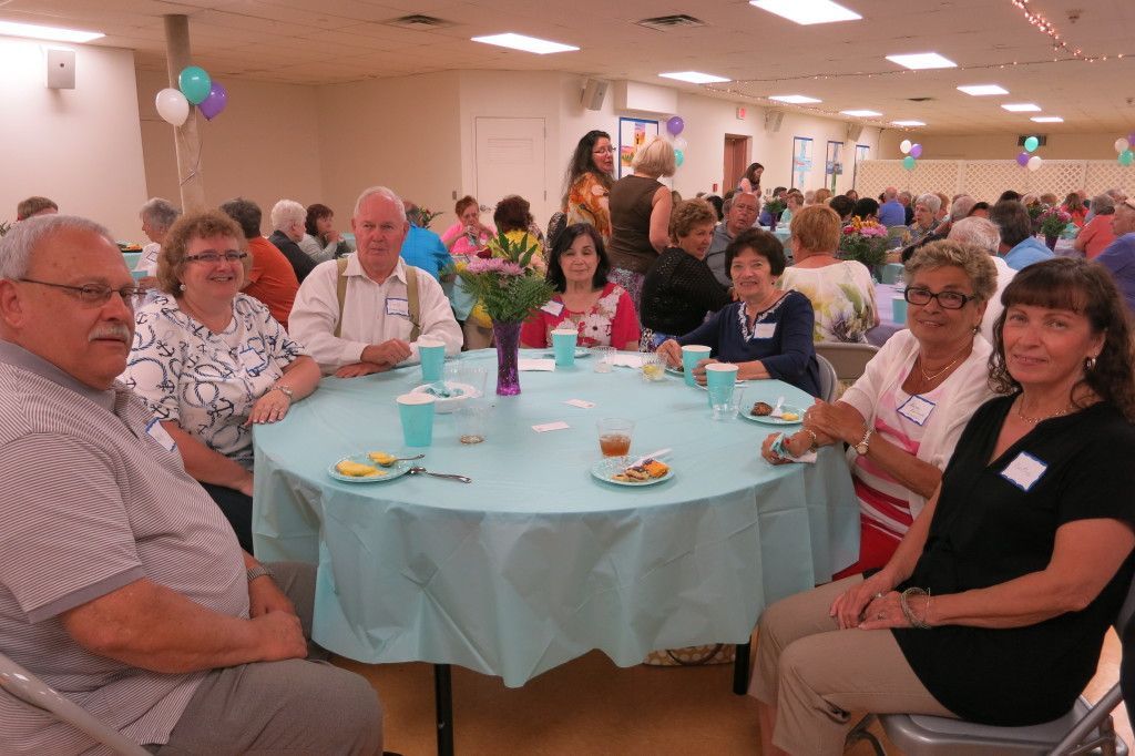 People seated around a round table at a community event in a decorated banquet hall