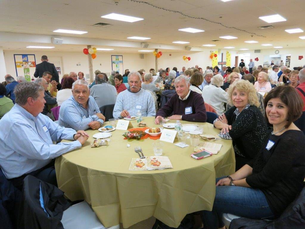People seated at round tables in a bright banquet hall, eating and chatting.
