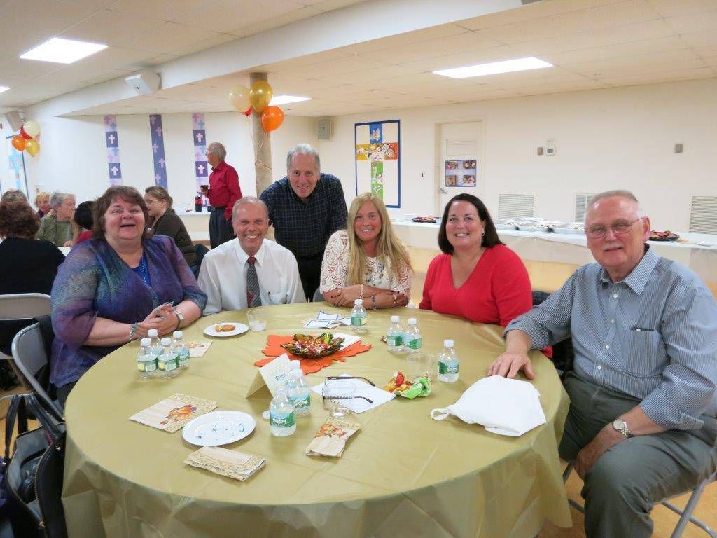 People seated around a table at a community gathering in a bright hall