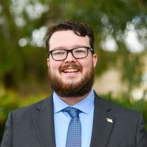 A young man in a suit and tie is smiling for the camera.