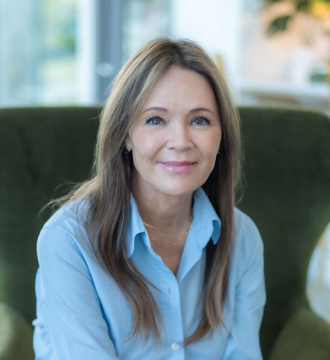 A woman in a blue shirt is sitting in a green chair.