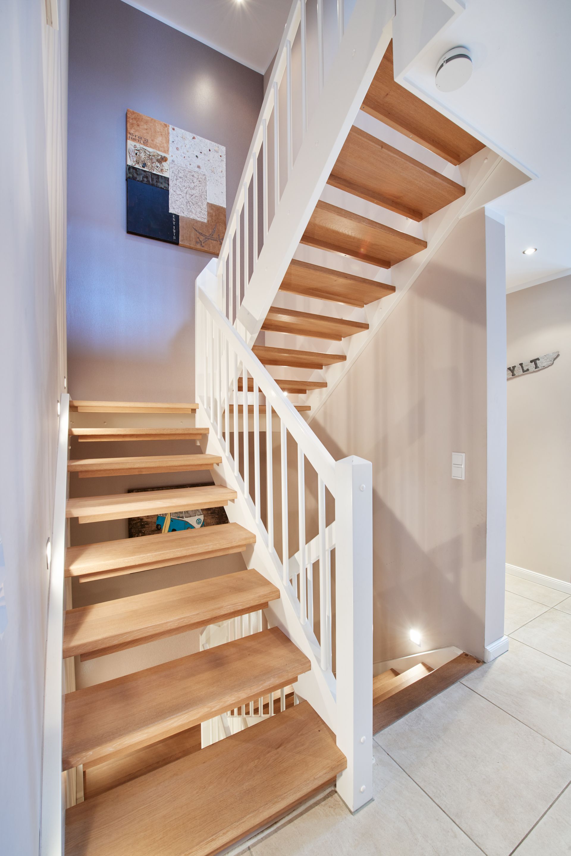 Holztreppe im Innenbereich mit weißem Geländer und Fliesenboden in einem modernen Haus