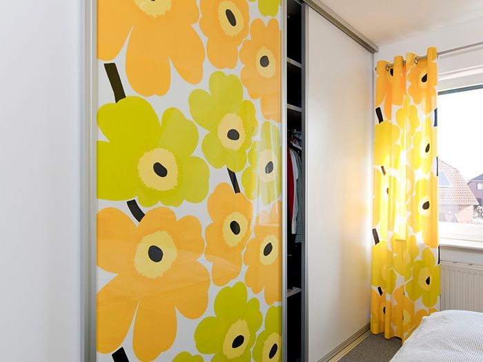 Leuchtend bunte, blumengemusterte Schiebetüren mit gelben und orangen Blumen in einem Schlafzimmer bei einem Fenster
.