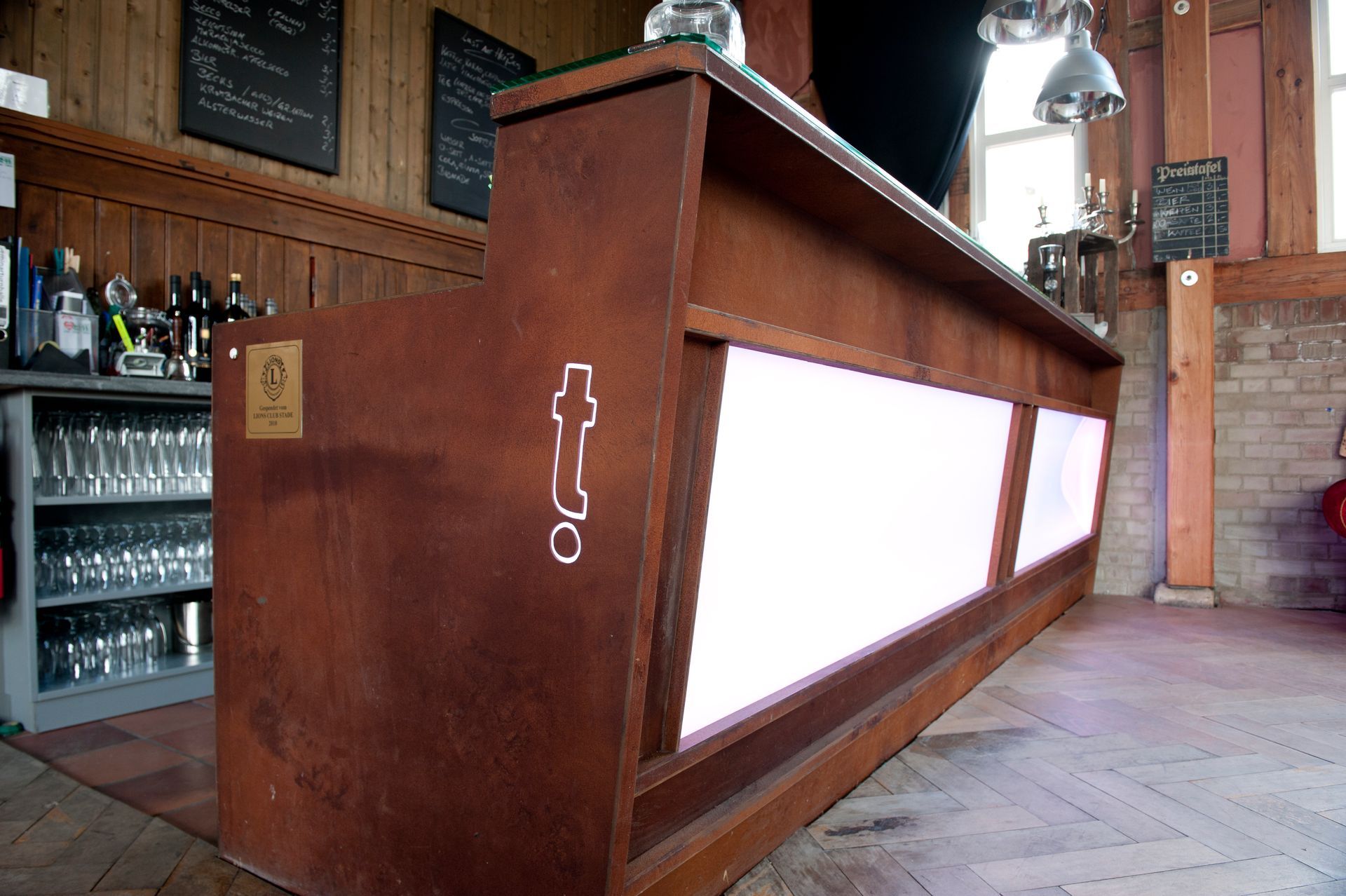 Bartheke aus Holz mit beleuchteten weißen Paneelen in einem rustikalen Pub-Interieur