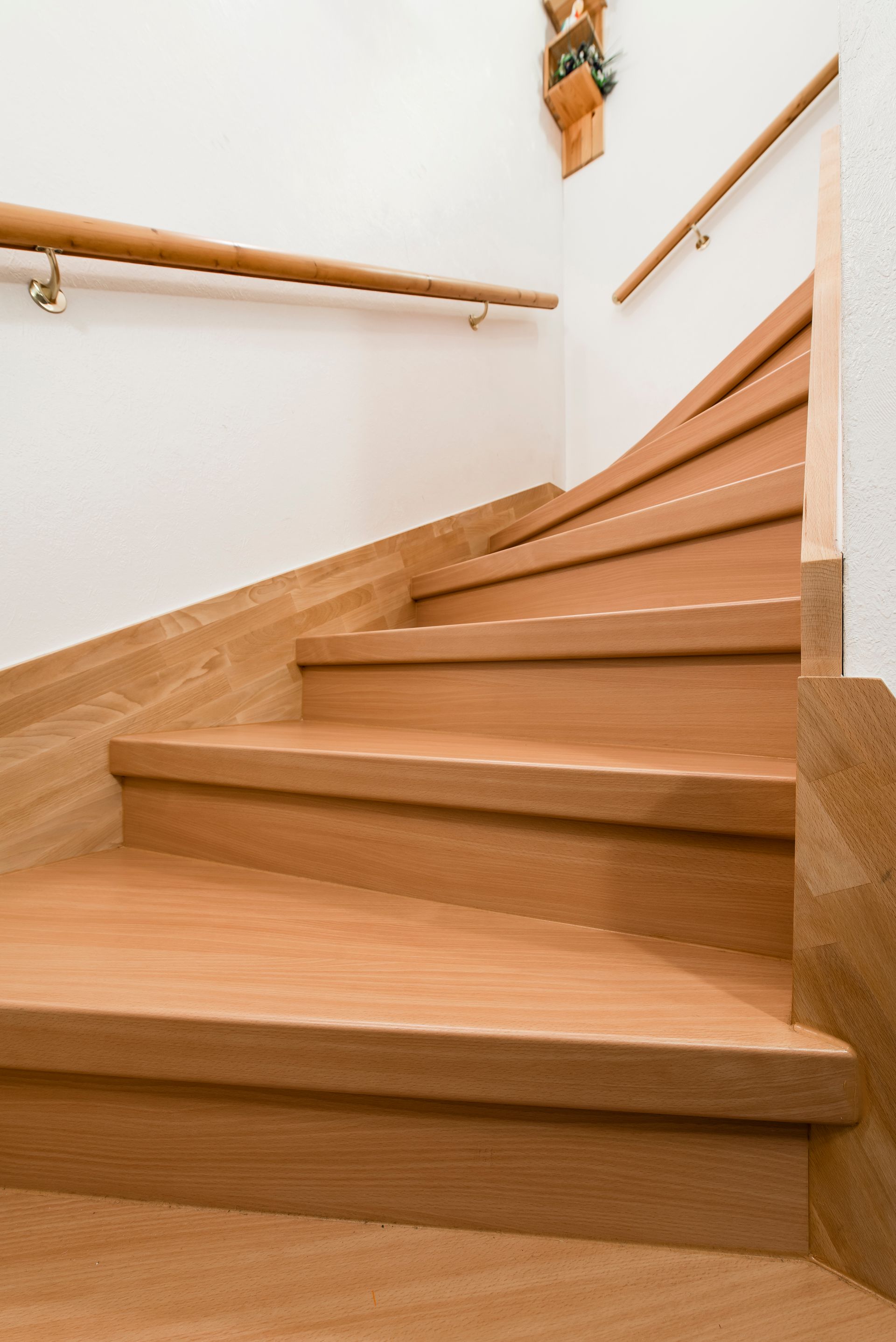 Holztreppe mit weißen Wänden und Handläufen, von unten nach oben betrachtet.