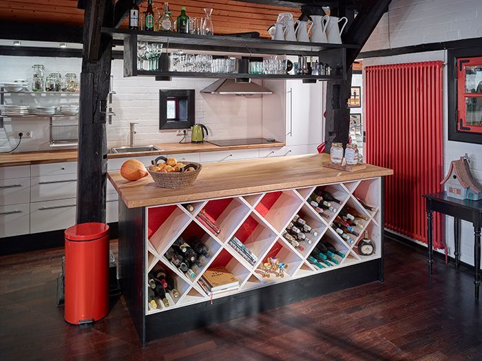 Moderne Küche mit Kochinsel aus Holz, Weinregal, roten Akzenten und dunklen Holzböden