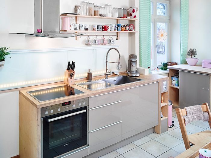 Helle, moderne Küche mit Spüle, Kochfeld, offenen Regalen und Fliesenboden in Fensternähe