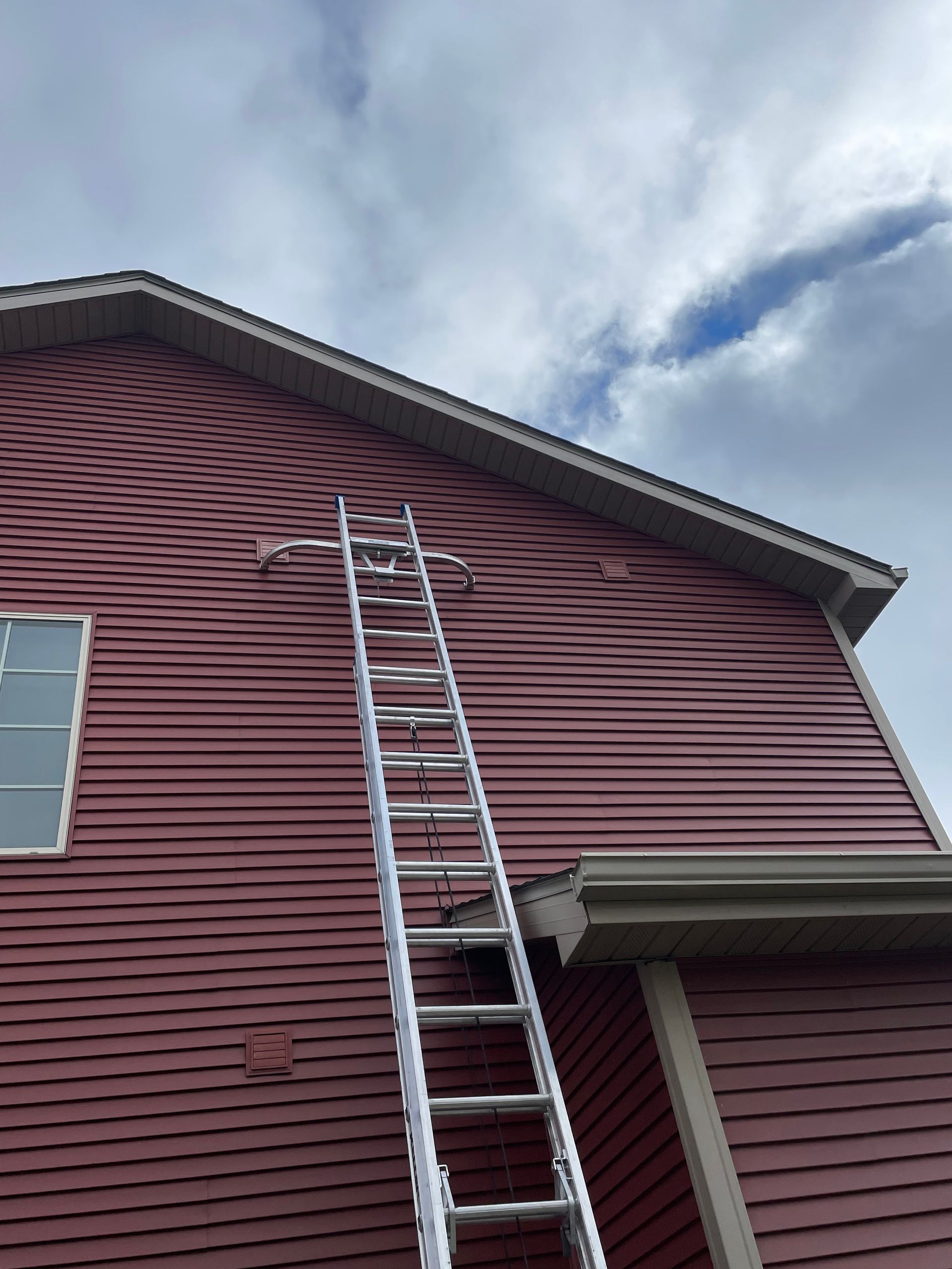 A ladder is attached to the side of a red house.