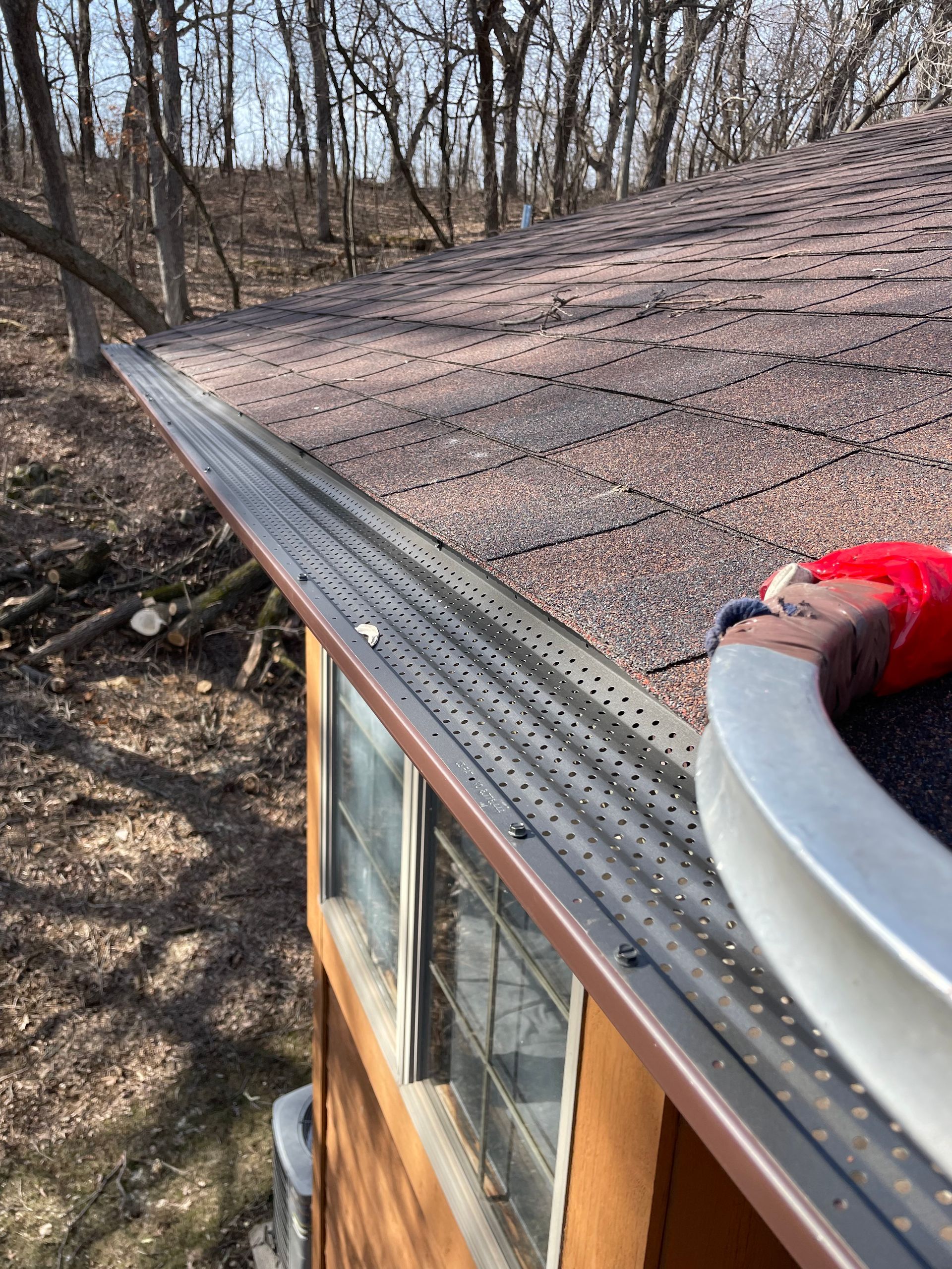 A person is fixing a gutter on the roof of a house.