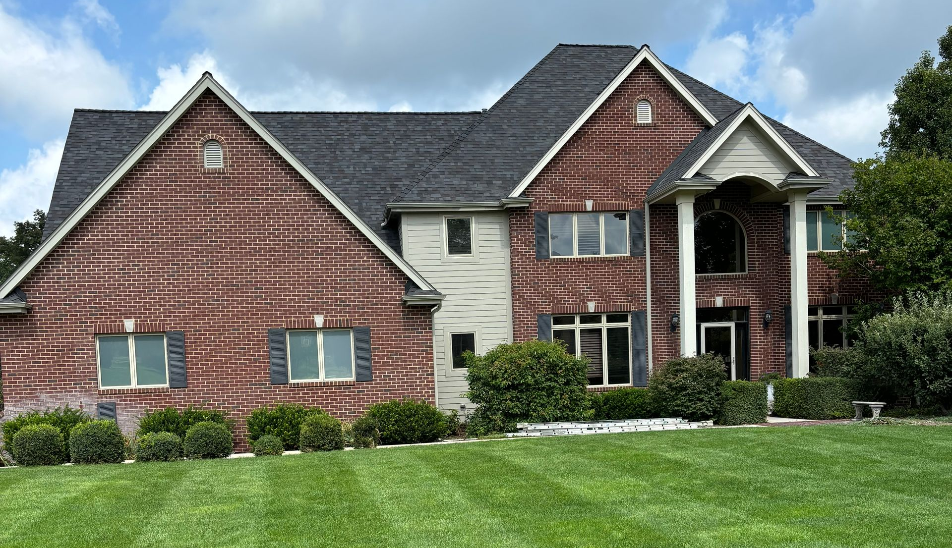 Large Janesville, WI home with newly installed gutters across a complex brick and siding roofline.