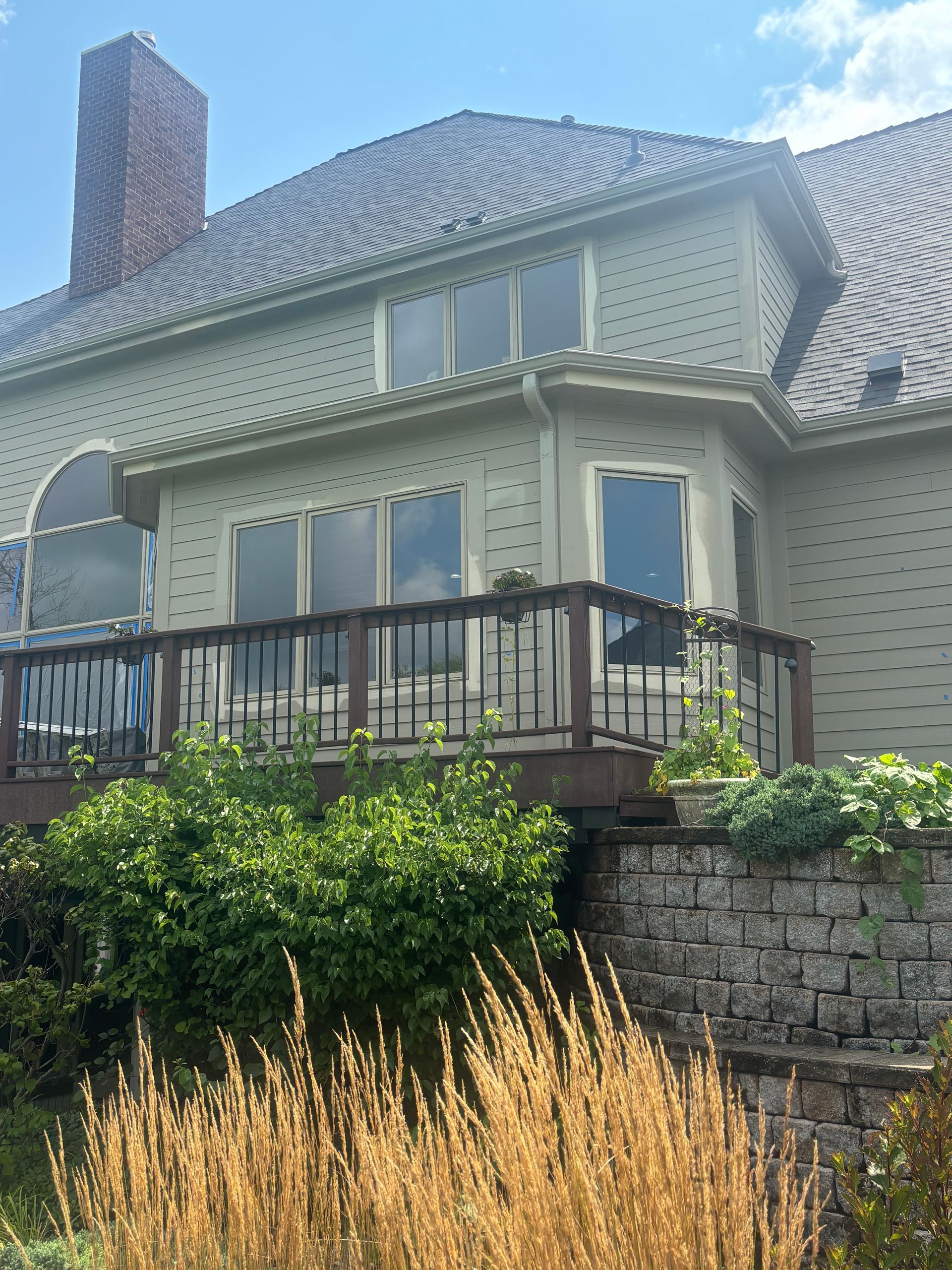 New gutters installed above a raised deck on a large Janesville home with light-colored siding.