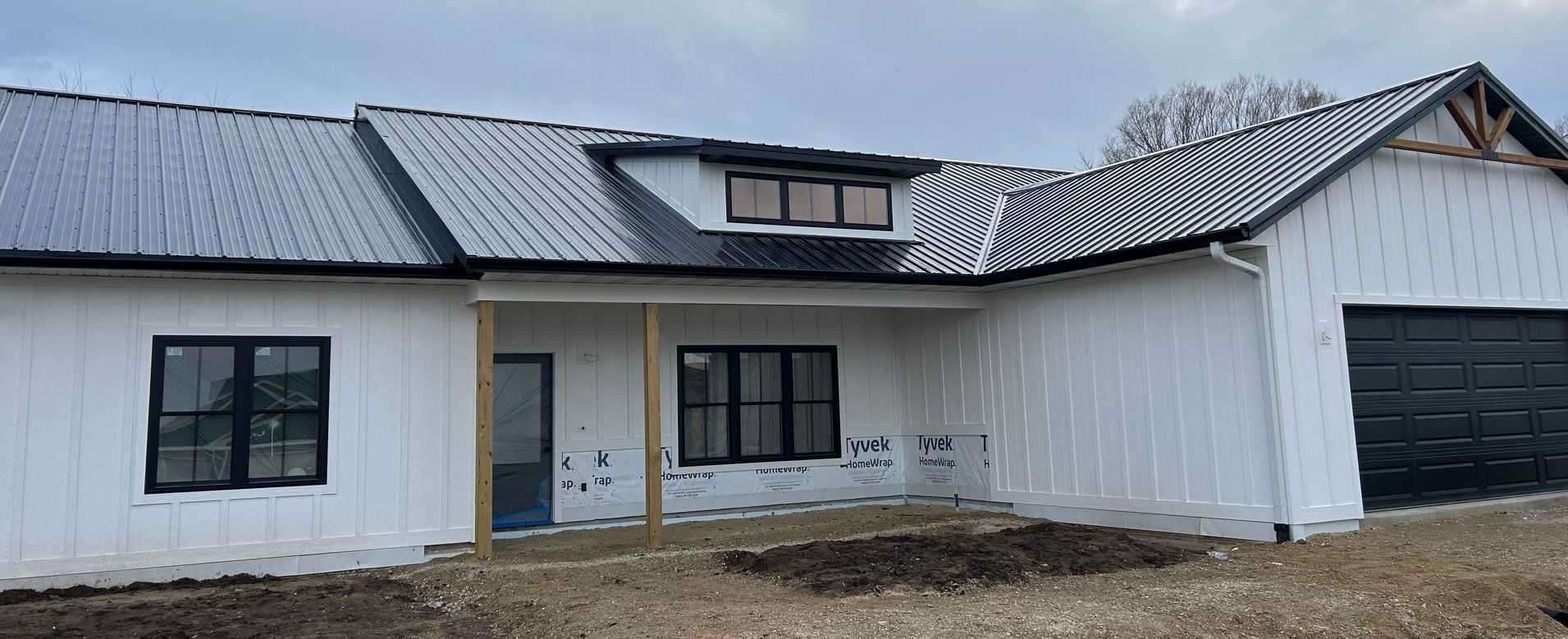 A white house with black windows and a black garage door is being built.