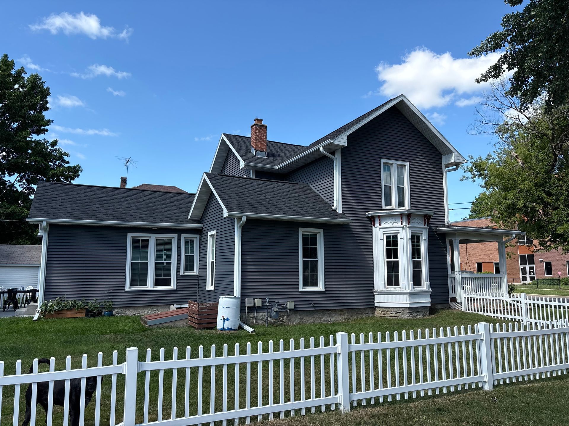 Front view of a historic Madison home featuring new white gutters, soffit, fascia, and dark blue siding.