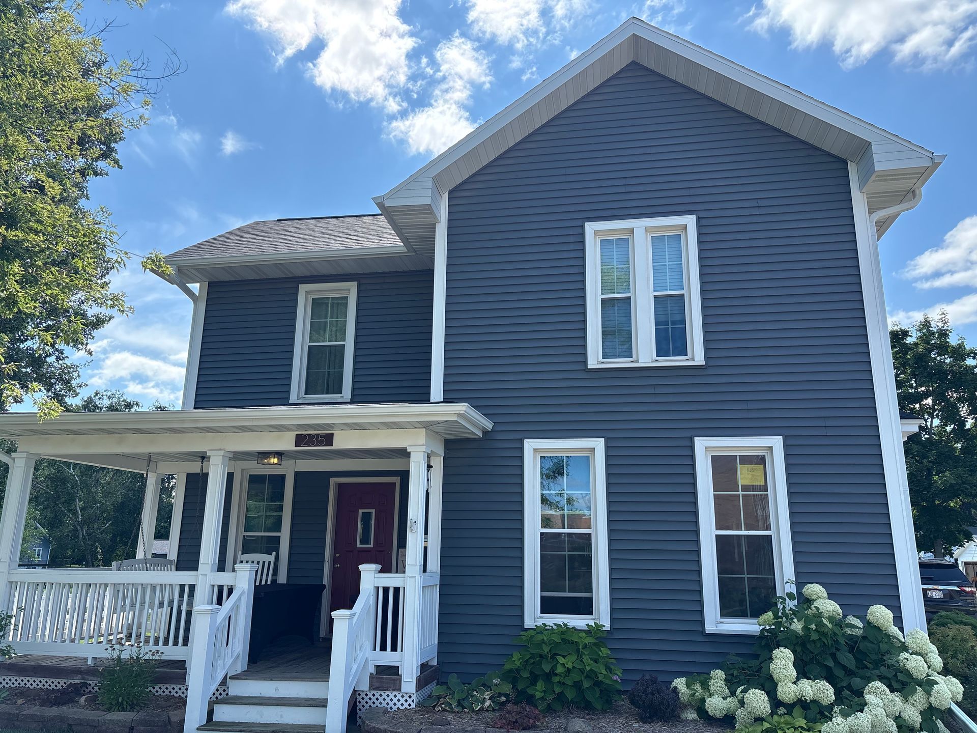 New white gutters and downspouts installed on a dark blue historic home in Madison, Wisconsin.