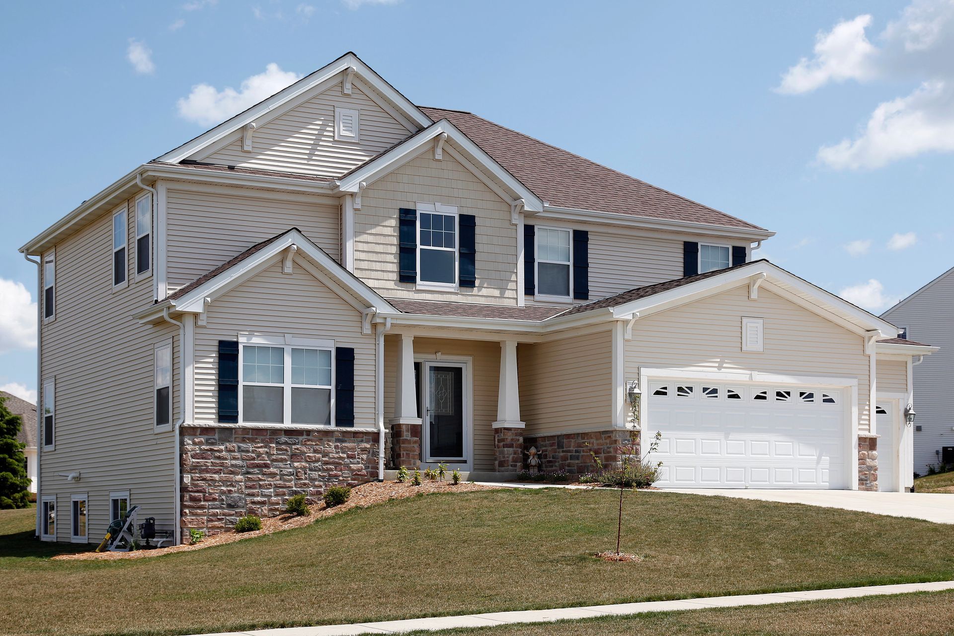 A large house with a white garage door and black shutters