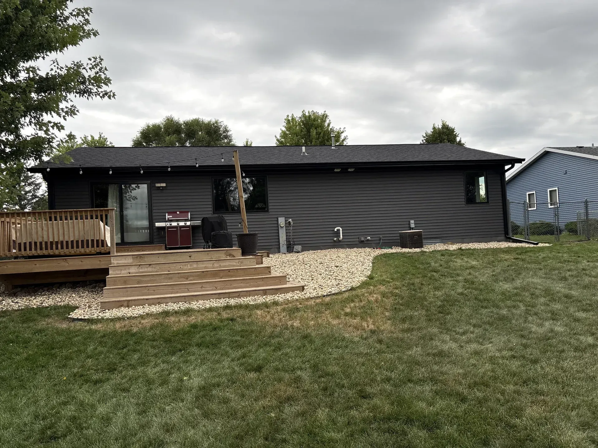 New black gutters and downspout directing water away from the rear deck and foundation of a Janesville, WI home