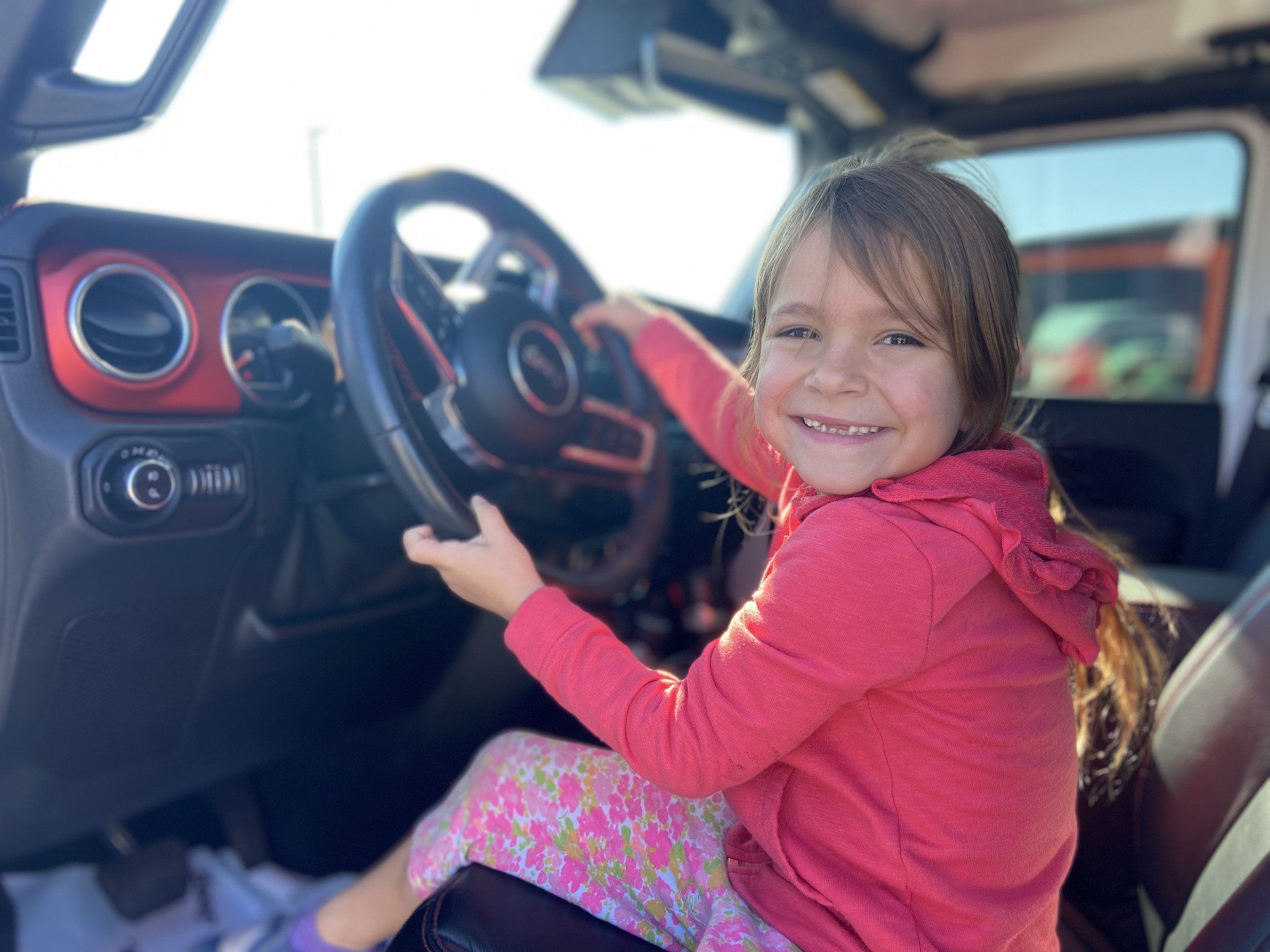 young girl sitting in drivers seat of jeep