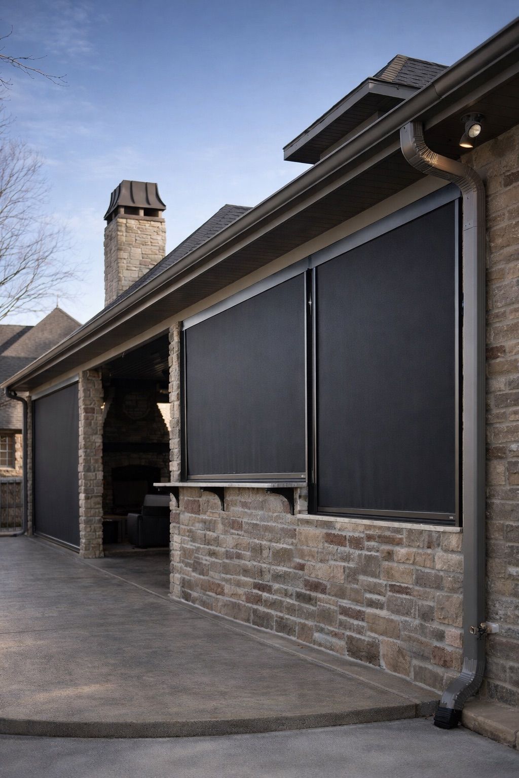 Stone house exterior with dark window shades and a covered driveway