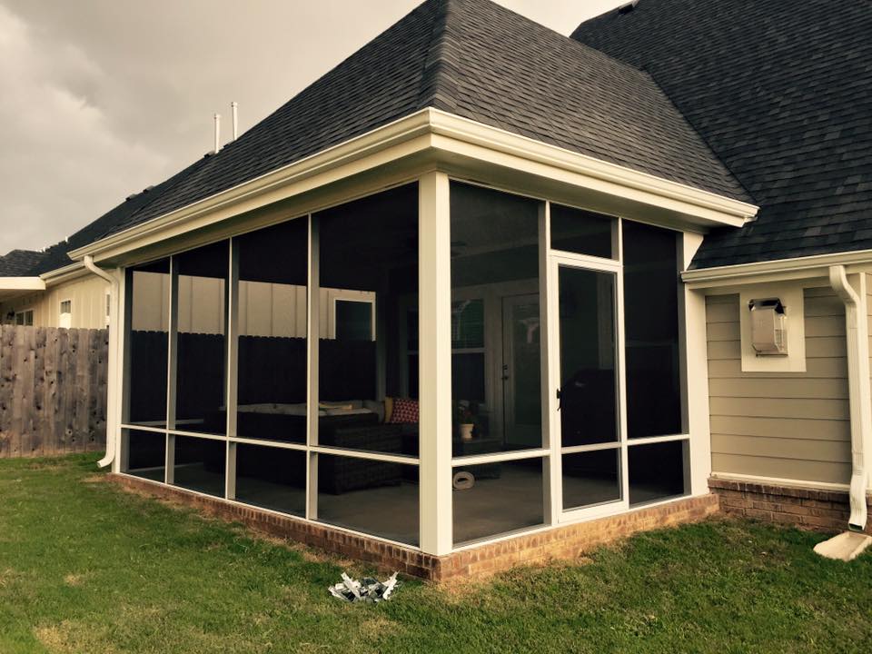 Screened back porch on a beige house with a dark roof and grassy yard