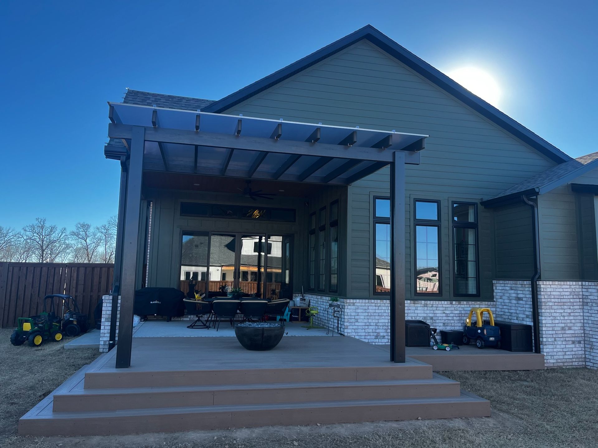 Modern house entrance with covered porch, steps, and large front windows at dusk