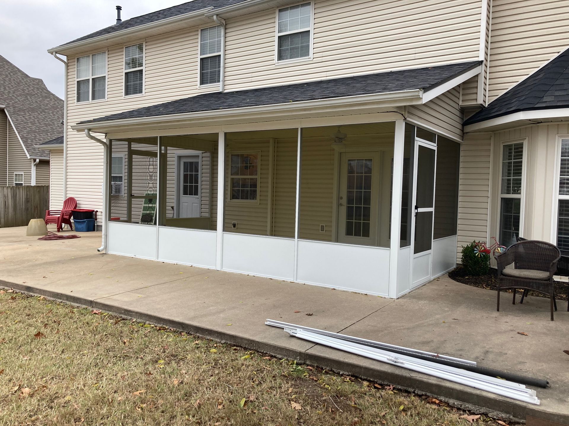 Back patio sunroom with white screened enclosure and ramp by a beige two-story house