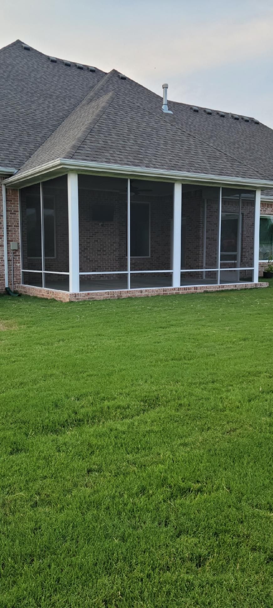 Covered patio attached to a house with screened porch and green lawn