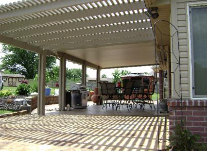 Covered patio with lattice roof, outdoor dining table, chairs, grill, and striped sunlight on the floor.