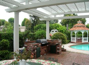 Covered patio with grill, white columns, and a poolside gazebo in a landscaped backyard