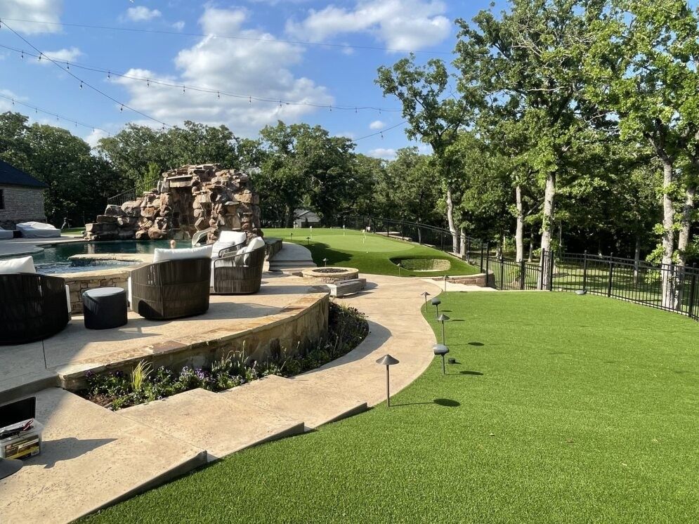 Outdoor park with a fountain, stone seating, and green lawn under a blue sky