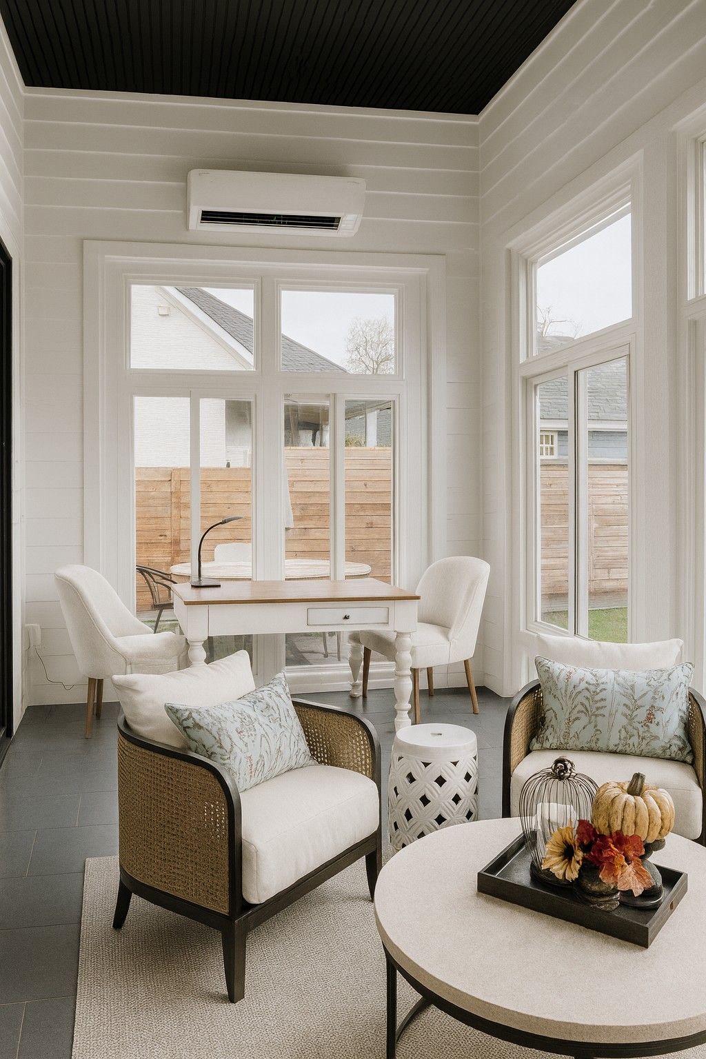 Cozy sunroom with wicker chairs, small dining table, and round coffee table by bright windows