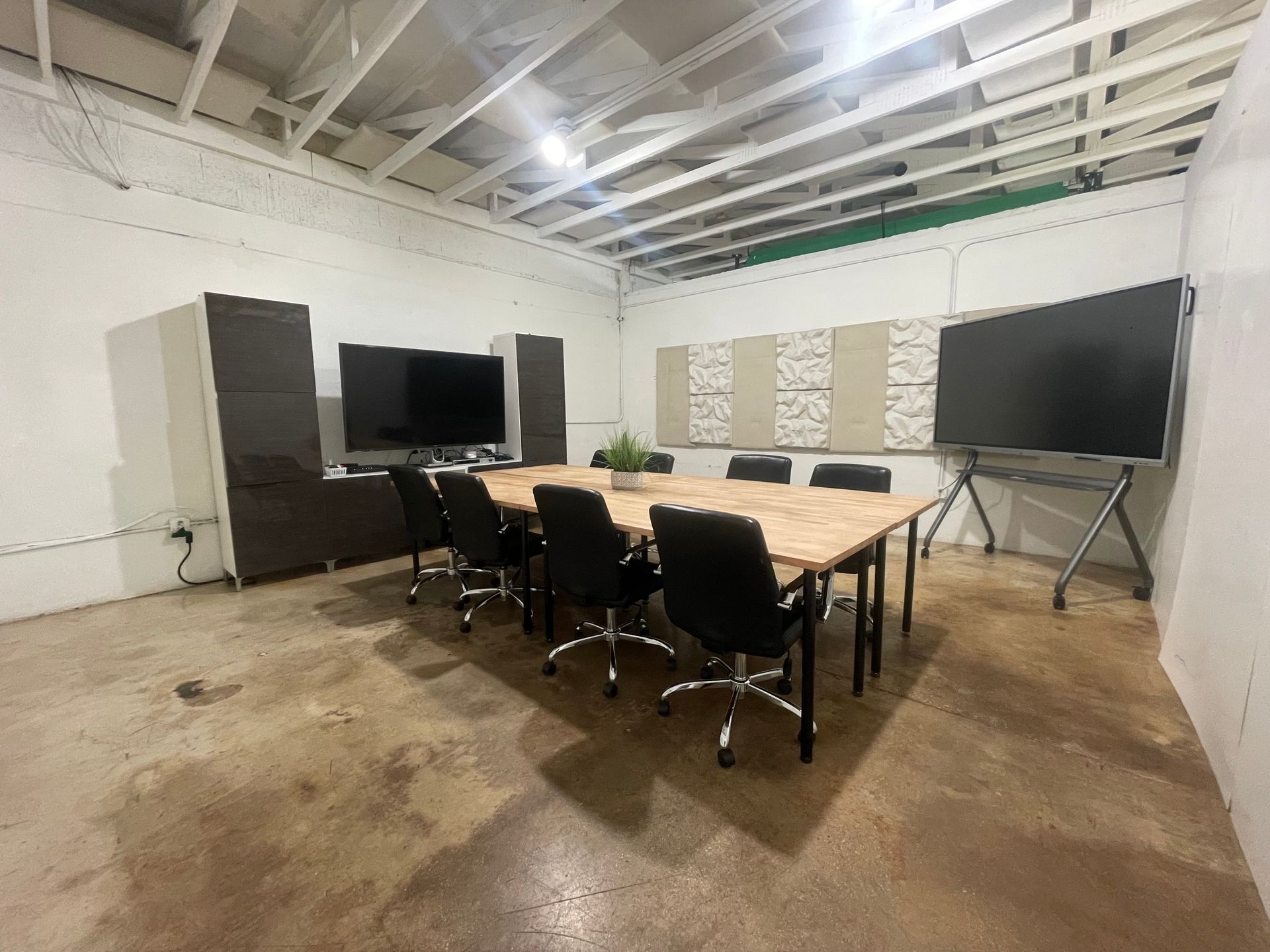 Conference room with a long table, chairs, screens, and sound panels.