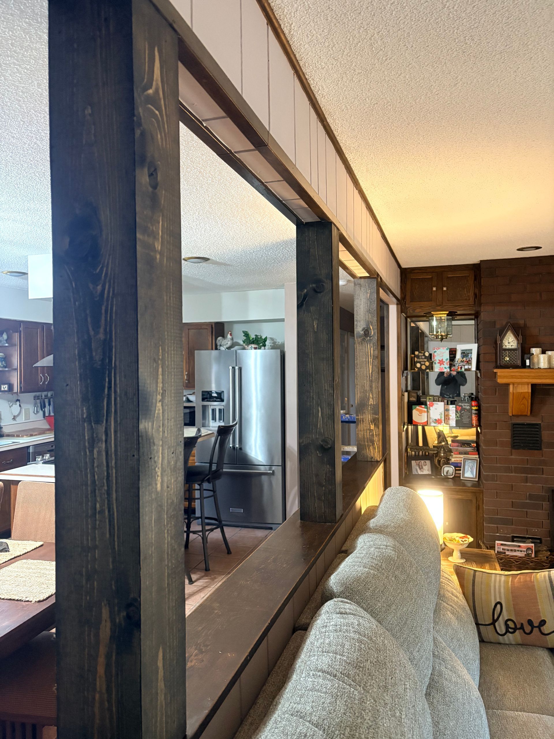 A view from a living room through a decorative wooden room divider into a kitchen with stainless steel appliances.