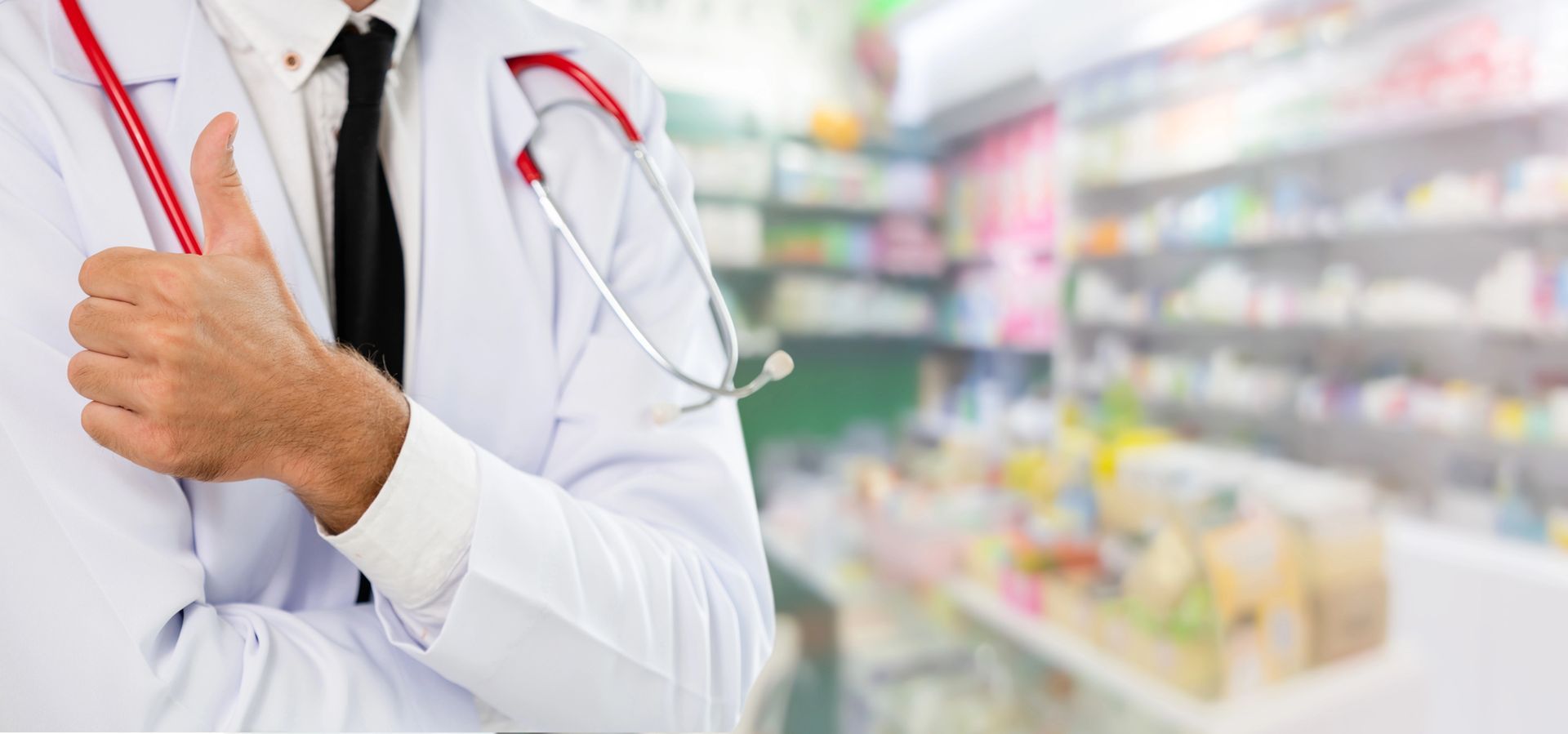 Doctor in a white coat with a red stethoscope in a pharmacy aisle