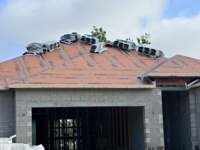 House roof under construction with stacked roofing materials on the orange shingles
