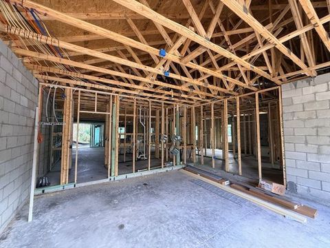 Interior of unfinished house with exposed wooden roof trusses, cinder block walls, and framed rooms